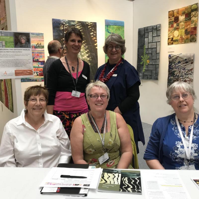 Festival of Quilts 2018 – SAQA members stewarding the SAQA Global exhibit on display - photo credit: Thilo Schueller
