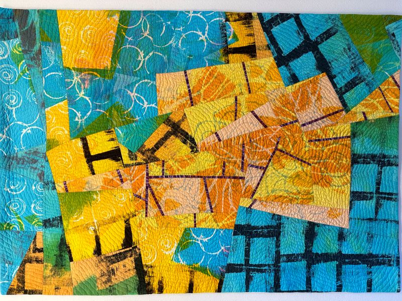 Brenda H. Smith - Faultlines (a quilt made up of fractured geometric pieces with surface printing. Yellow shapes are surrounded by blue green)