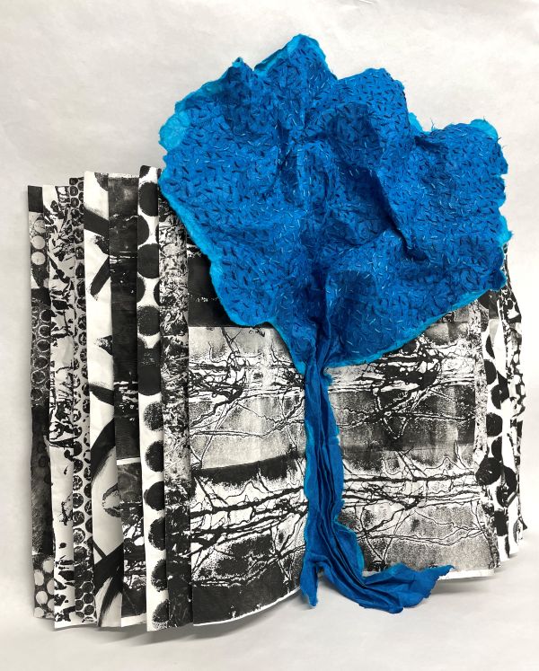 Laura Wasilowski - Blue Book on Blue Trees (a bright blue, densely stitched tree on a black and white fabric book that  is printed with various textures)