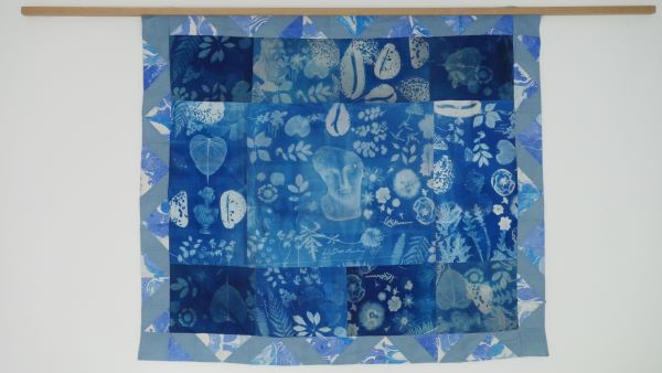 Image Courtesy of the artist: Lydia Donohue (wall hanging in shades of blue and white, leaves, faces, busts, and ferns are printed on the fabric)
