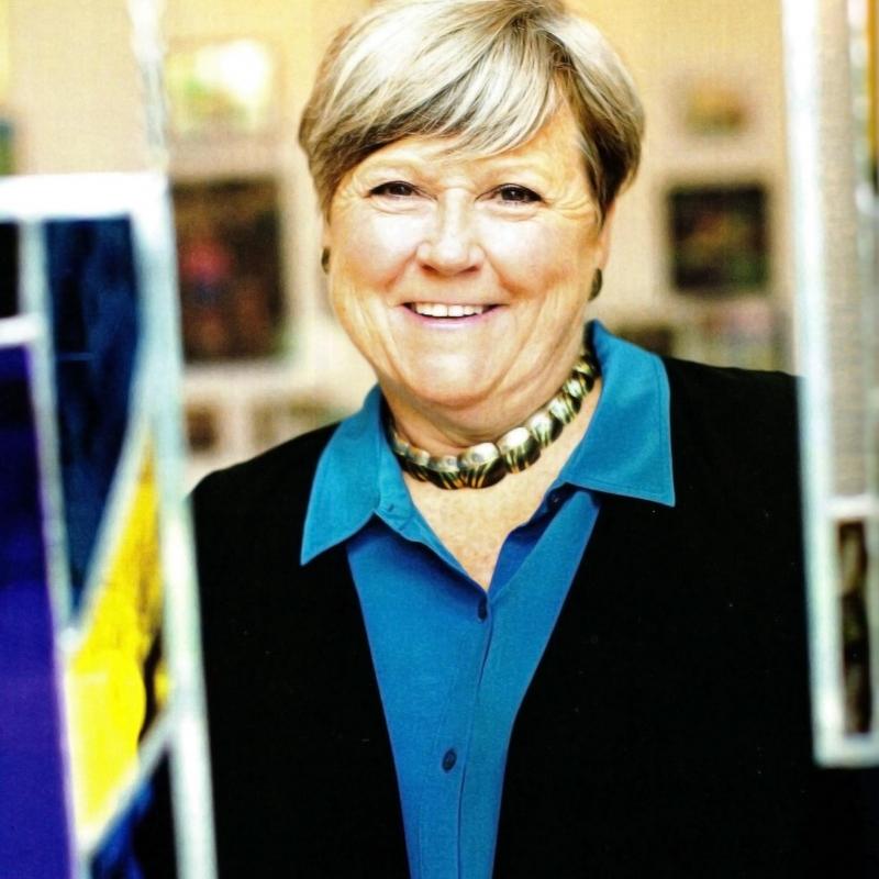 Nancy Campbell is looking at the camera and smiling. She is wearing a black blazer and a blue collared shirt.