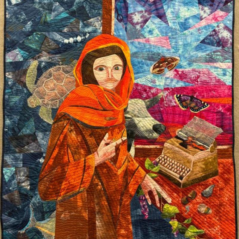 Susan Yanos - From the Webs She Wove Sprang Life (quilt of a woman in an orange robe with images floating around--a turtle, cow, butterflies, fish, and typewriter)