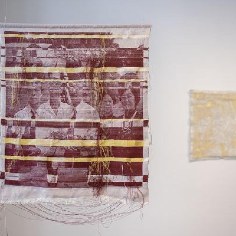 Kỷ Niệm Ngày Cưới: Burgundy and Gold - Thương Hoài Trần (textile wall handing of photos printed in burgundy on white fabric with lots of handing threads and bands of yellow)